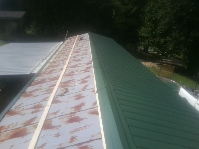 Old rusted panels beside newly installed green metal roofing — Wind Damage Roof Repair by Roofing Brothers in Tecumseh